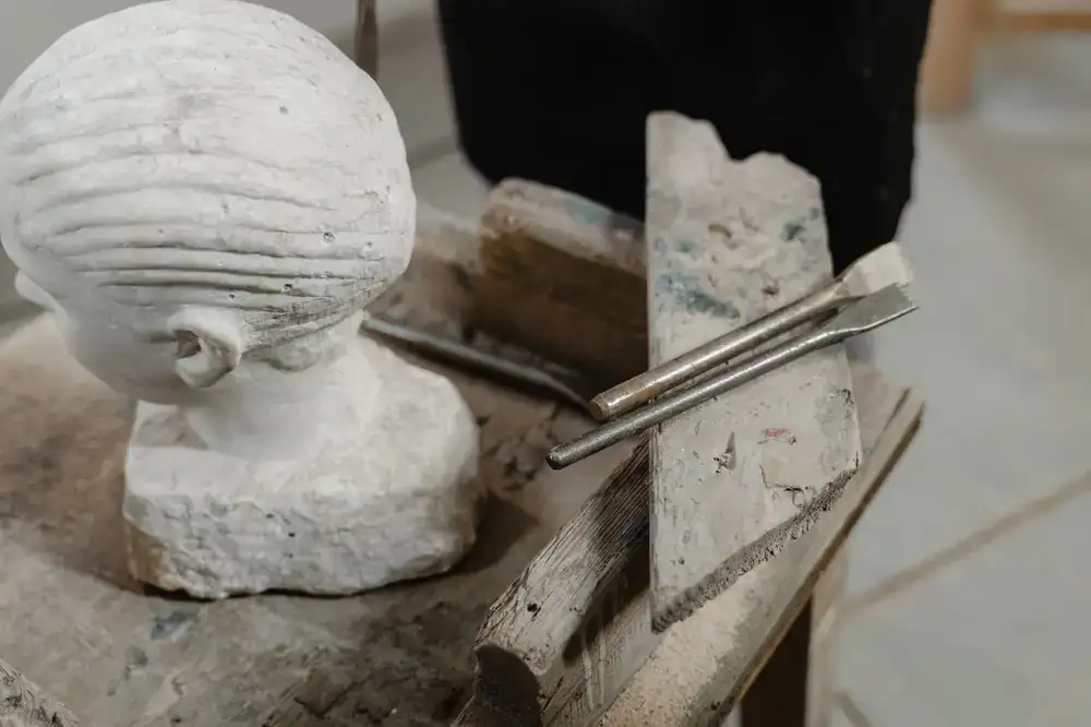 Artisan hands carving a wooden puppet head with small chisels